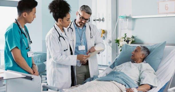 A photo of a hospital ward with healthcare staff in action and doctors checking on a recovering patient highlights the role of infection control and teamwork in promoting wellness.